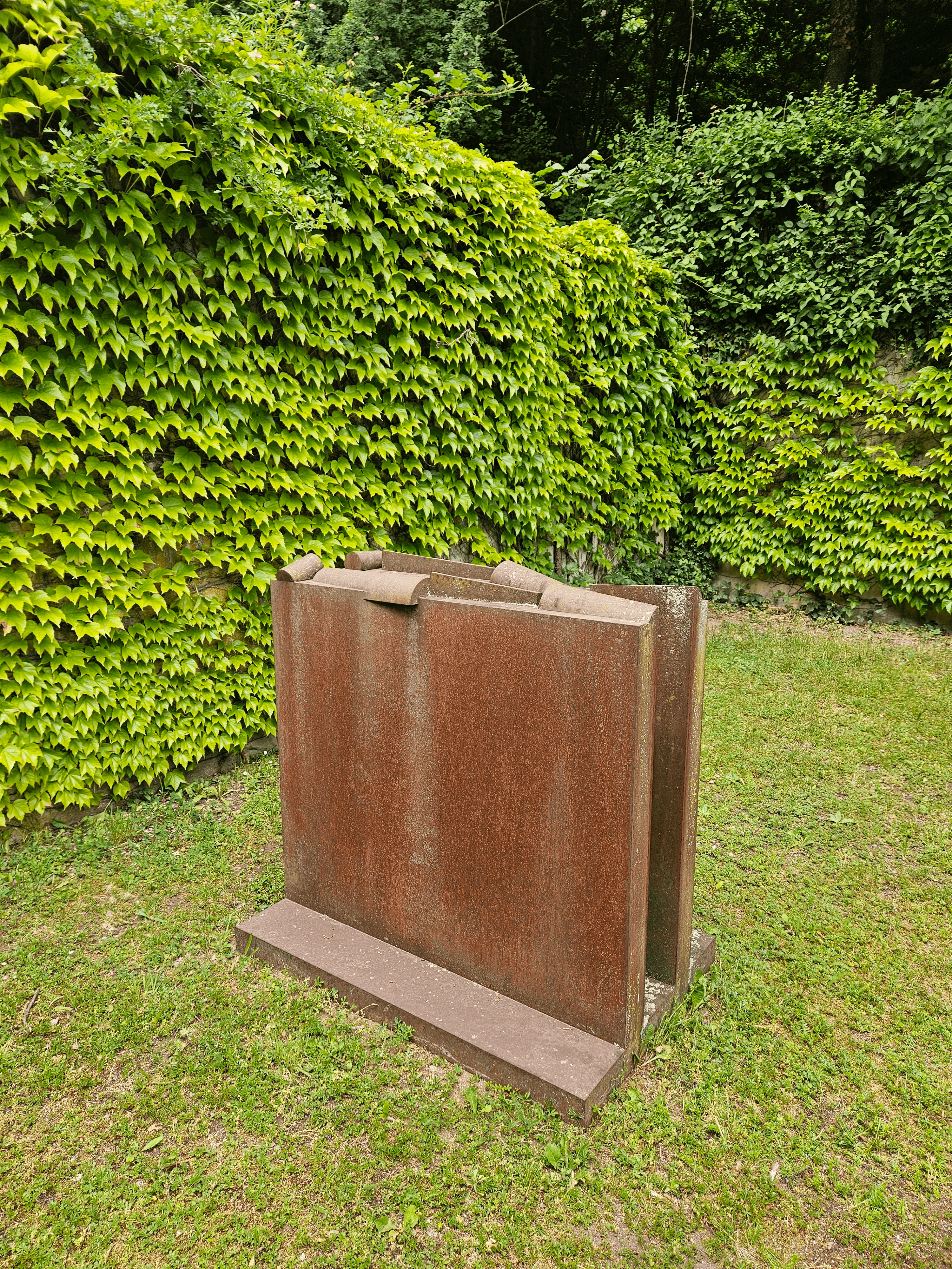 Das Kunstwerk aus Eisen steht auf der Grünfläche vor der Großen Werkhalle / Kugelhalle