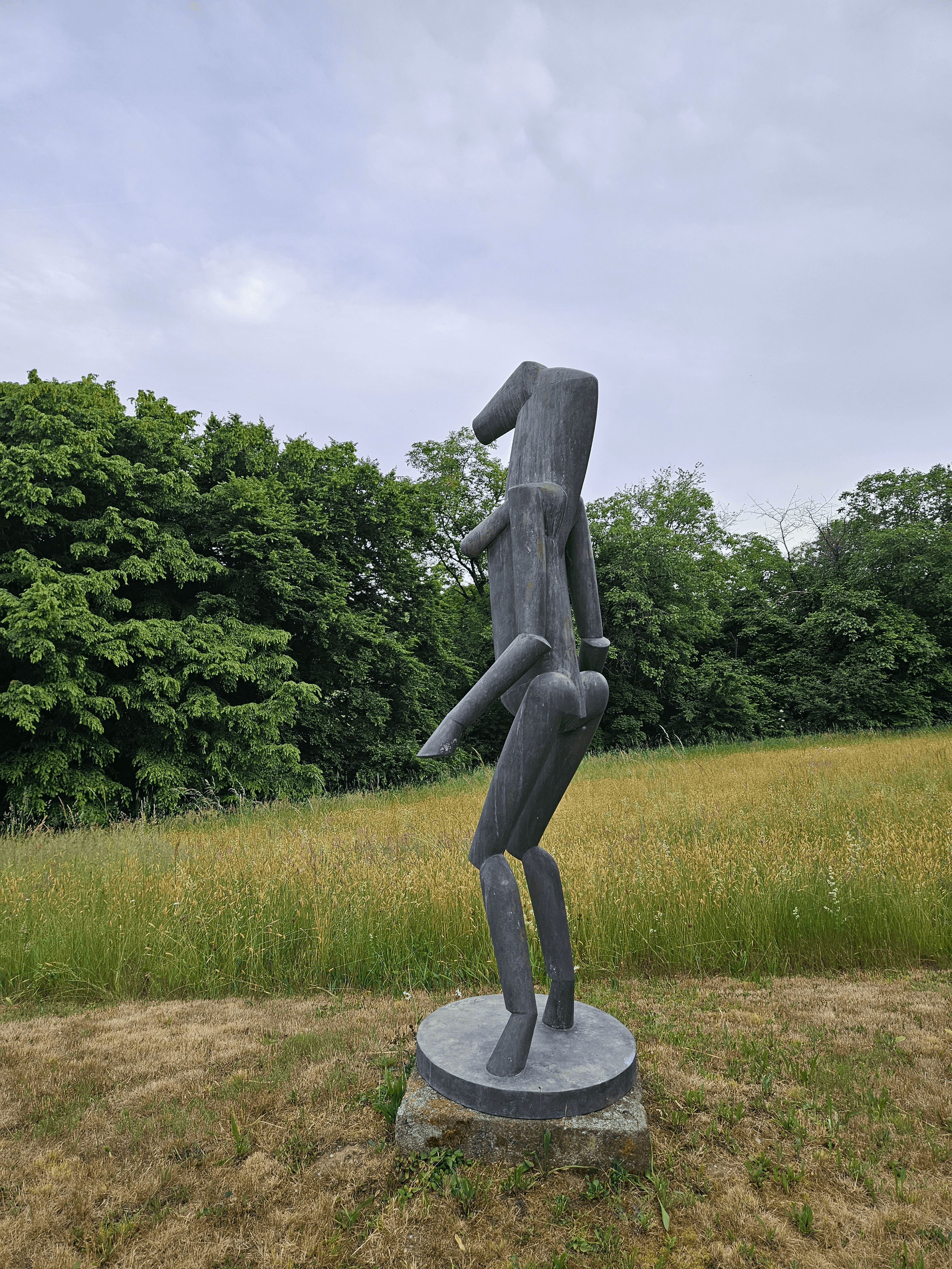 Das Kunstwerk aus Bronze steht auf einer Grünfläche bei dem Hof von Fritz Koenig 