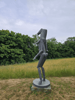 Das Kunstwerk aus Bronze steht auf einer Grünfläche bei dem Hof von Fritz Koenig 