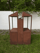 Das Kunstwerk aus Eisen steht auf einer Grünfläche vor dem Hof von Fritz und Maria Koenig