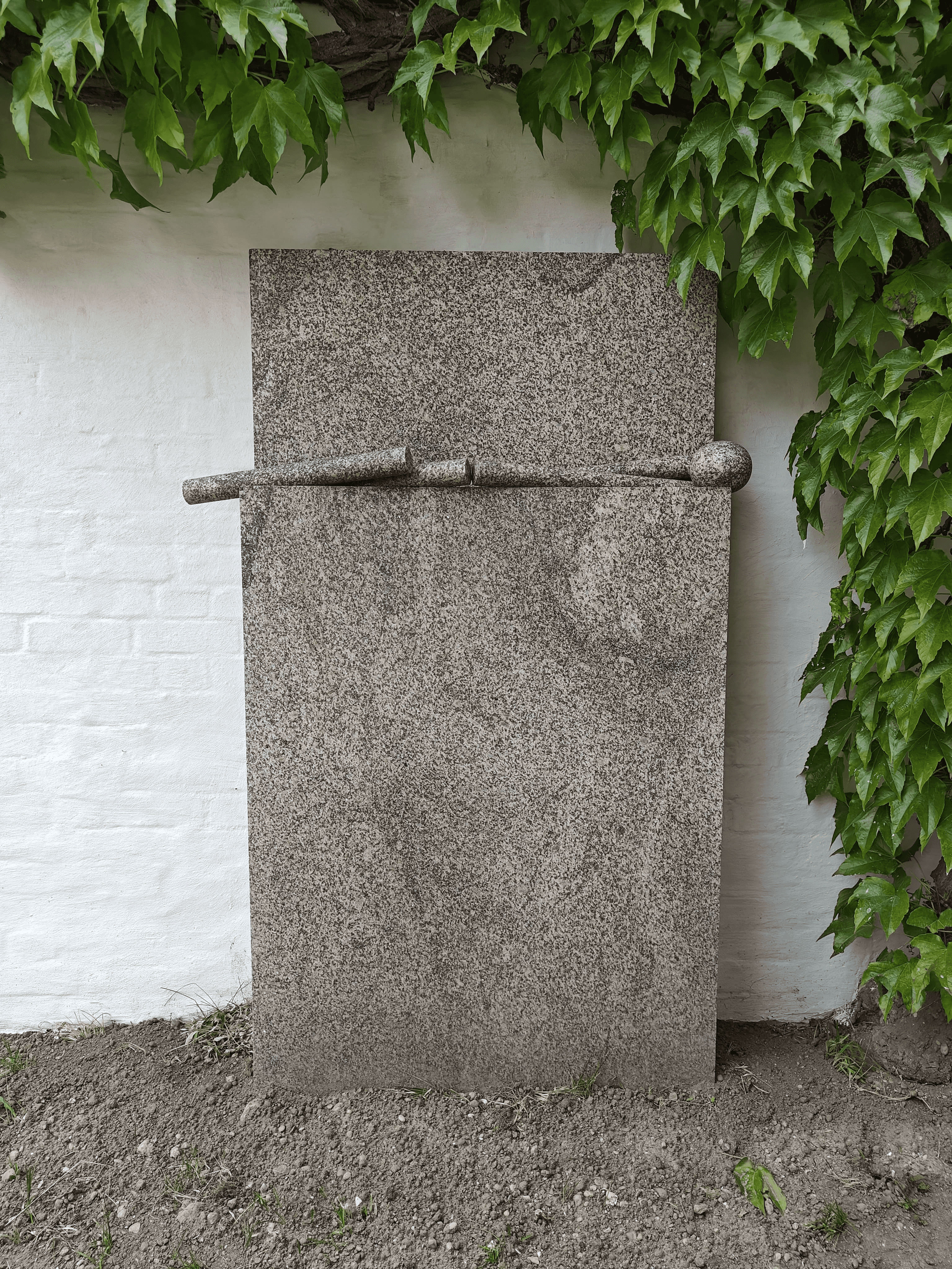 Das Kunstwerk aus Granit steht vor einer Mauer des Vierseithofs von Fritz und Maria Koenig