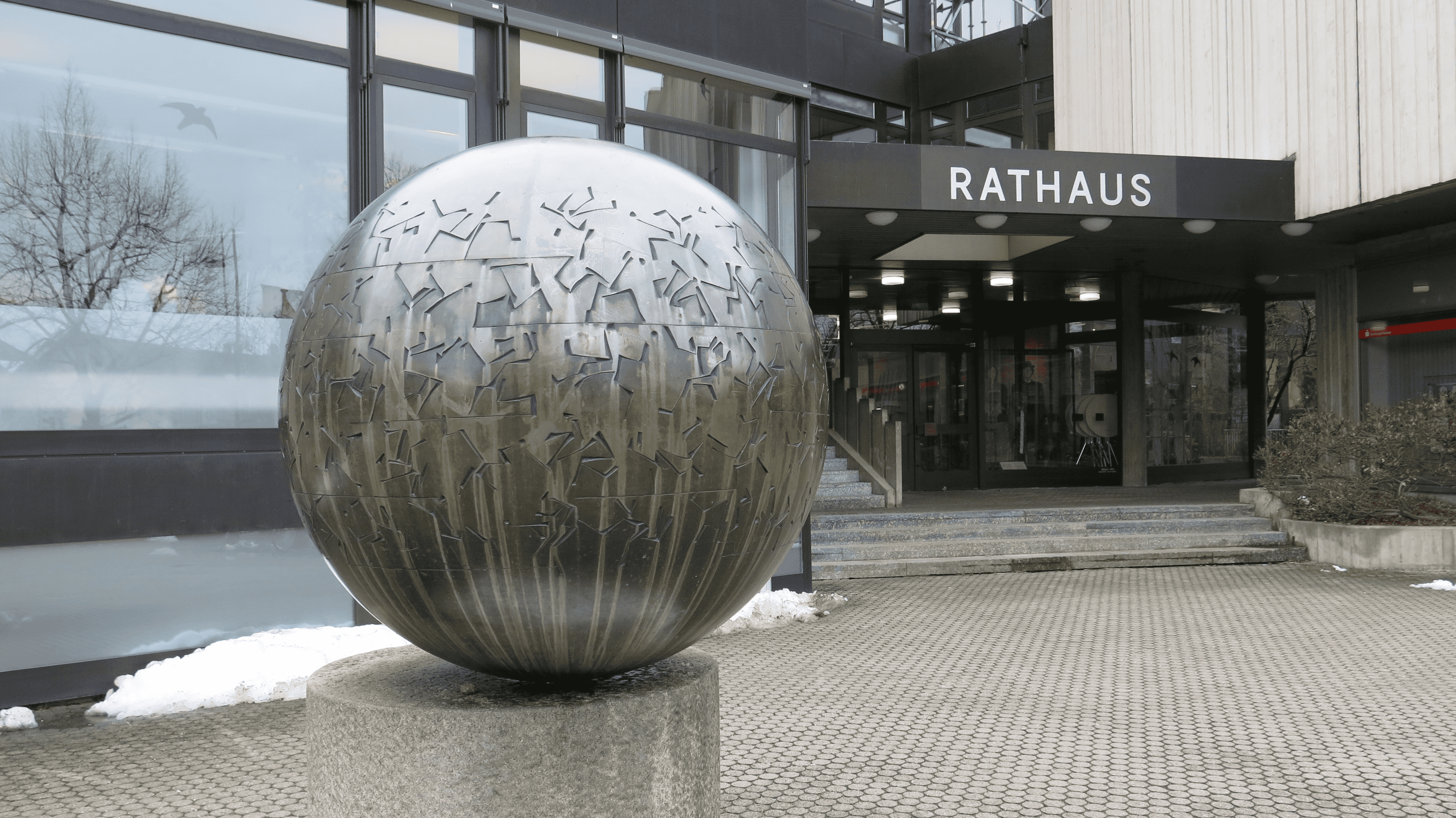 Das kugelförmige Kunstwerk aus Bronze steht vor dem Rathaus der Gemeinde Unterföhring